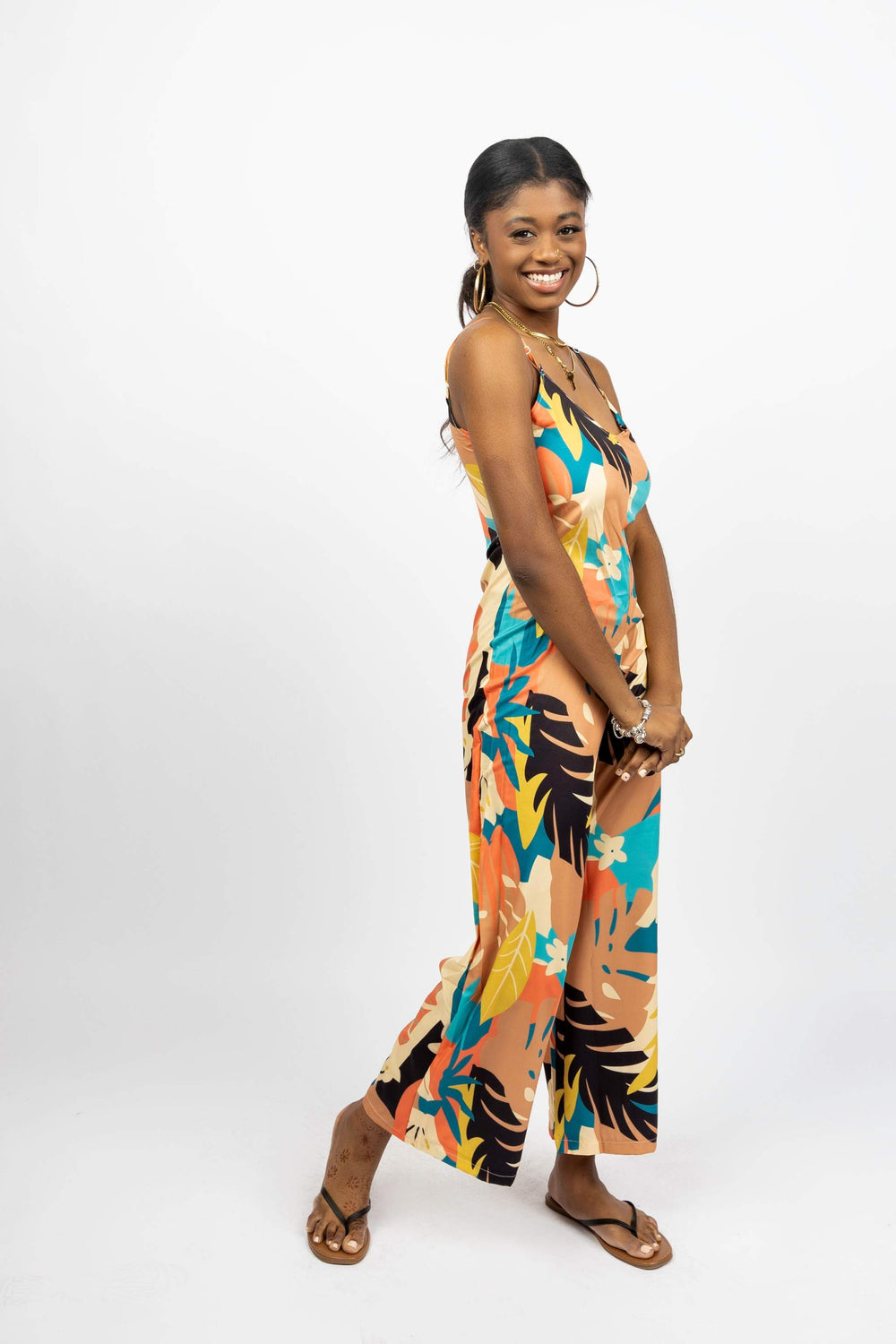 Woman wearing colorful Summer Breeze Jumpsuit with adjustable spaghetti straps and tropical print