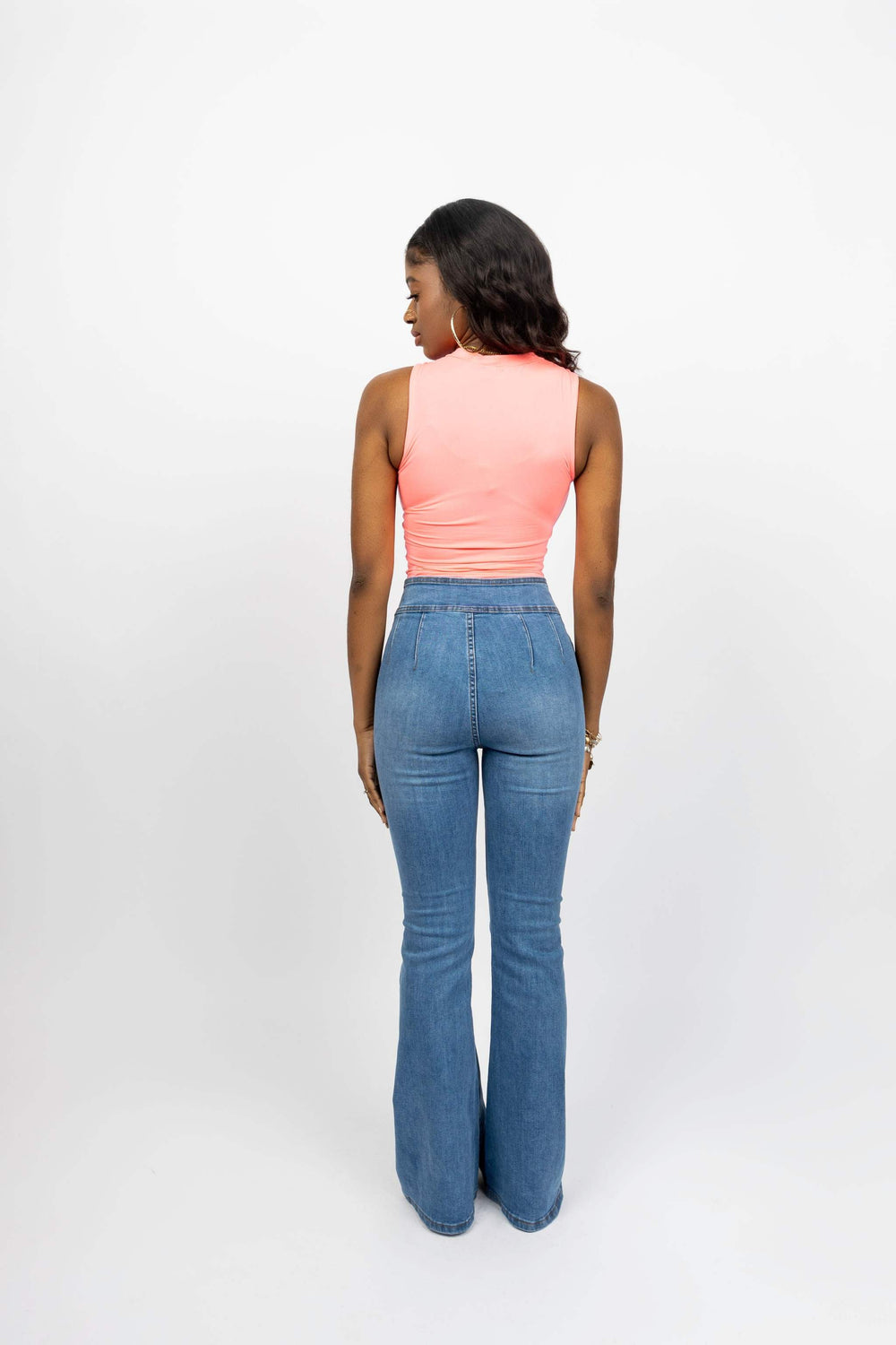Woman wearing high-rise flare jeans with wide waistline and two buttons, viewed from the back